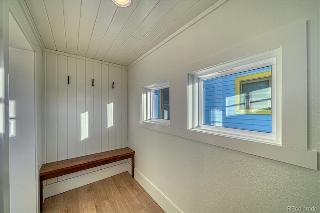 interior space with wooden walls, wood ceiling, baseboards, and light wood finished floors