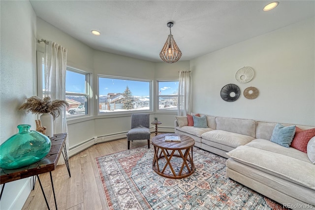 living area with light wood finished floors, baseboard heating, recessed lighting, and an inviting chandelier