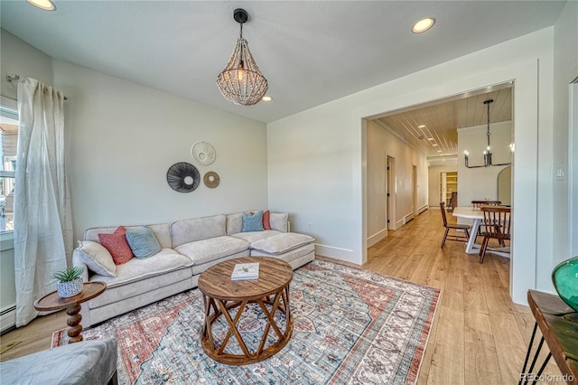 living room featuring baseboards, recessed lighting, light wood-type flooring, and a chandelier