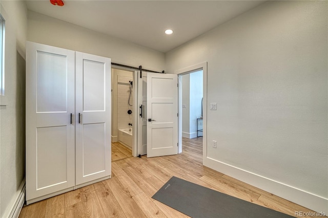 workout area with a baseboard heating unit, baseboards, light wood-type flooring, a barn door, and recessed lighting