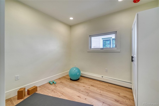 exercise area featuring baseboard heating, recessed lighting, baseboards, and wood finished floors