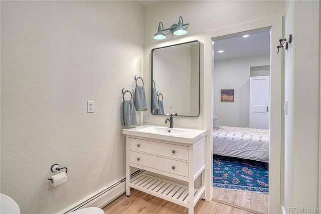 bathroom featuring a baseboard radiator, toilet, wood finished floors, and vanity