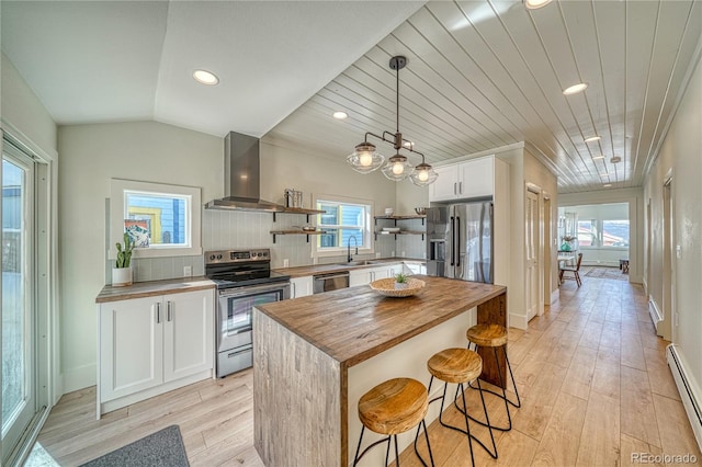 kitchen with open shelves, a sink, butcher block countertops, appliances with stainless steel finishes, and wall chimney exhaust hood