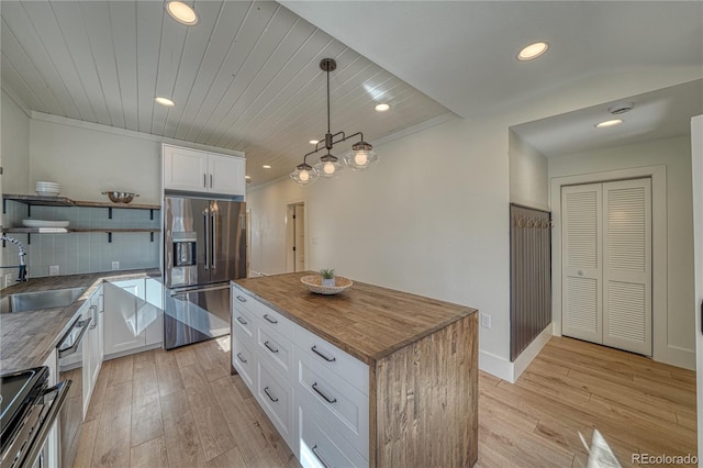 kitchen with open shelves, a sink, appliances with stainless steel finishes, light wood-type flooring, and butcher block counters