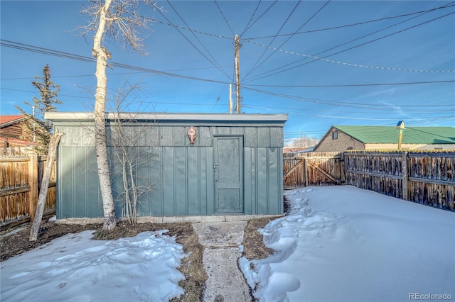 snow covered structure featuring an outdoor structure and a fenced backyard