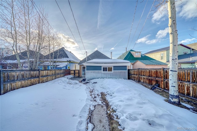 snow covered back of property featuring a fenced backyard