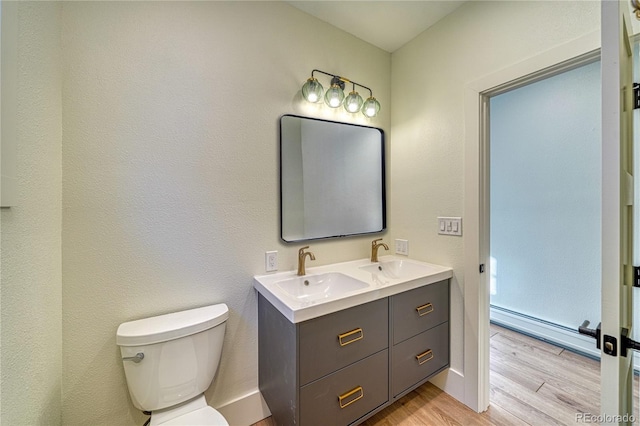 bathroom featuring baseboard heating, toilet, wood finished floors, and a sink