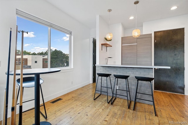 1711 Boulder St, Denver, CO 80211 - kitchen featuring a kitchen breakfast bar, light wood finished floors, modern cabinets, hanging light fixtures, and light countertops