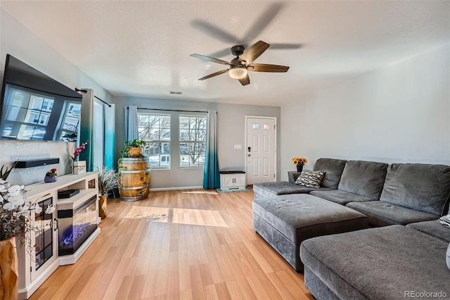 living room with visible vents, ceiling fan, light wood-style flooring, and baseboards