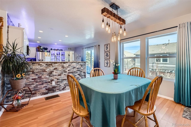 dining space with bar, recessed lighting, visible vents, baseboards, and light wood finished floors