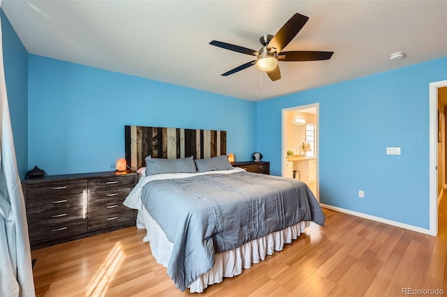 bedroom featuring light wood-type flooring, ceiling fan, baseboards, and ensuite bathroom