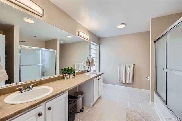 full bath featuring double vanity, shower / bath combination with glass door, tile patterned flooring, and a sink