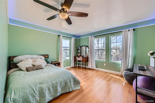 bedroom featuring wood finished floors, a ceiling fan, and baseboards