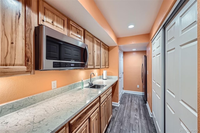 kitchen featuring refrigerator, dark wood-type flooring, a sink, baseboards, and stainless steel microwave