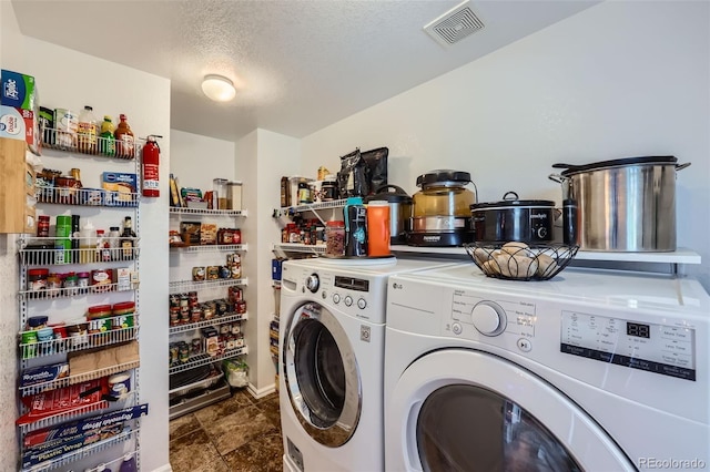 laundry area featuring laundry area, visible vents, a textured ceiling, and washing machine and clothes dryer