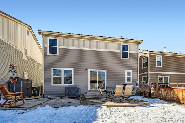 snow covered rear of property featuring entry steps and fence