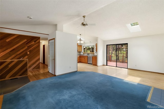 1343 Terri Ln, Woodland Park, CO 80863 - unfurnished living room featuring a skylight, light carpet, lofted ceiling, ceiling fan, and a textured ceiling