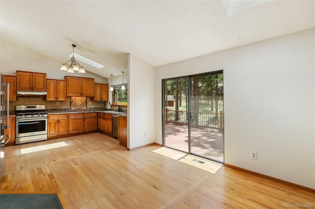 1343 Terri Ln, Woodland Park, CO 80863 - kitchen featuring brown cabinetry, stainless steel appliances, light wood-type flooring, vaulted ceiling, and a chandelier