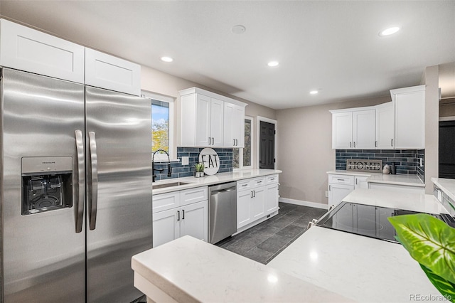 kitchen featuring stainless steel appliances, dark tile patterned floors, white cabinetry, backsplash, and sink