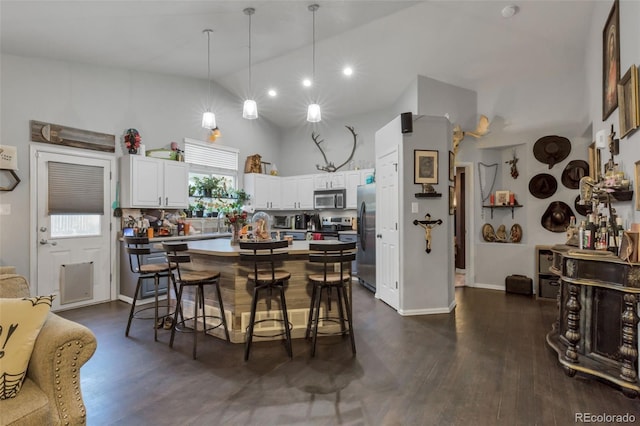 kitchen with a center island, dark hardwood / wood-style floors, white cabinets, hanging light fixtures, and appliances with stainless steel finishes