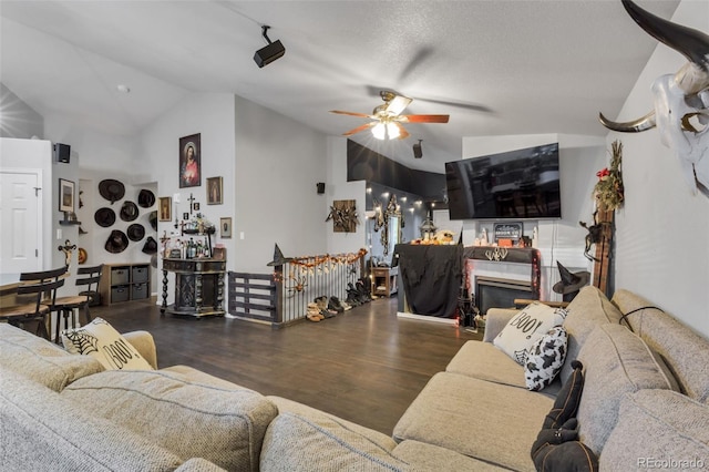 living room featuring lofted ceiling, ceiling fan, dark wood-type flooring, and a textured ceiling