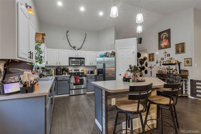 kitchen with light countertops, appliances with stainless steel finishes, dark wood finished floors, white cabinetry, and high vaulted ceiling