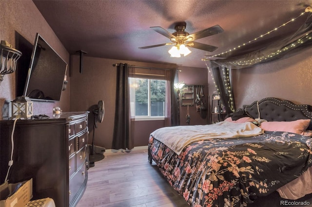 bedroom featuring light hardwood / wood-style flooring, a textured ceiling, and ceiling fan