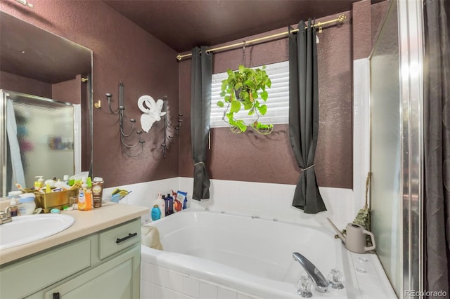 bathroom featuring a bath, a shower stall, vanity, and a textured wall