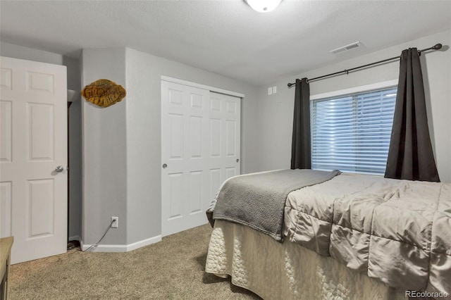 carpeted bedroom with visible vents, a closet, baseboards, and a textured ceiling
