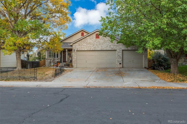 view of front of house featuring a garage, brick siding, driveway, and fence