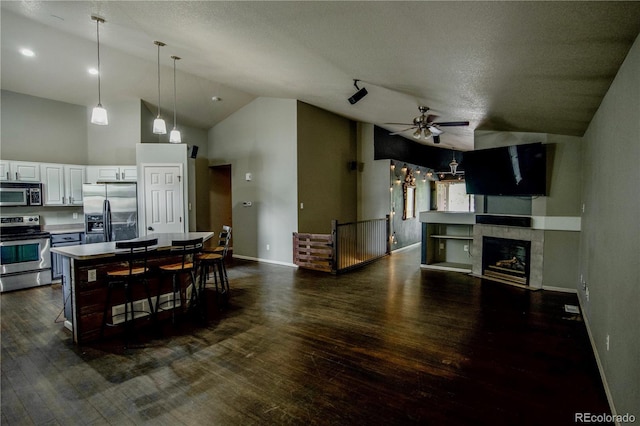 11384 Oakland Dr, Commerce City, CO 80640 - kitchen with stainless steel appliances, ceiling fan, baseboards, dark wood-type flooring, and high vaulted ceiling