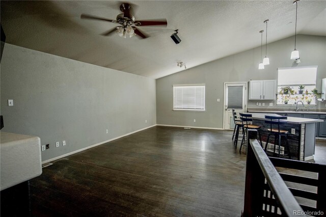 11384 Oakland Dr, Commerce City, CO 80640 - unfurnished living room featuring vaulted ceiling, a ceiling fan, dark wood finished floors, a sink, and baseboards