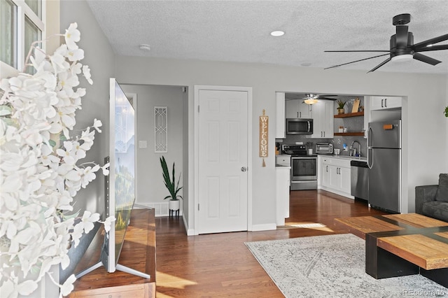 living room with ceiling fan, a textured ceiling, and dark hardwood / wood-style flooring