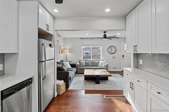 kitchen featuring white cabinets, stainless steel appliances, dark hardwood / wood-style floors, and backsplash