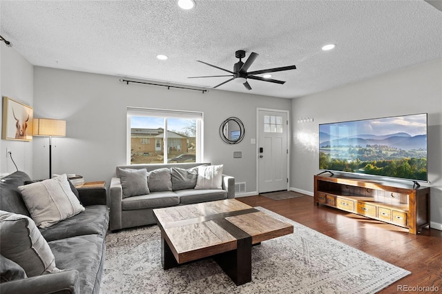 living room with ceiling fan, dark hardwood / wood-style floors, and a textured ceiling