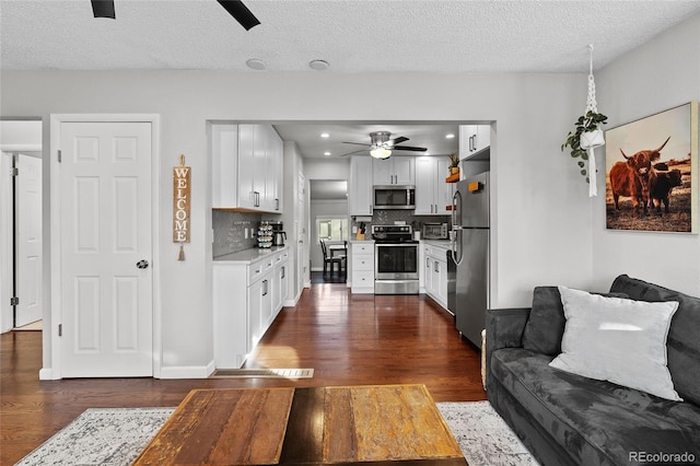 living room with ceiling fan, dark hardwood / wood-style floors, and a textured ceiling