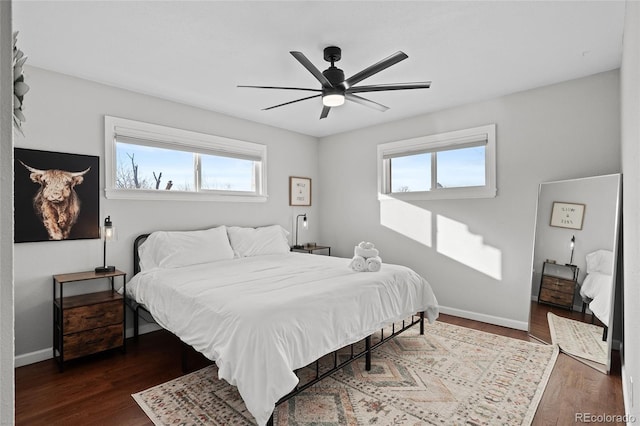 bedroom featuring ceiling fan, multiple windows, and dark hardwood / wood-style floors