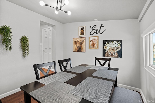 dining area with wood-type flooring and a notable chandelier