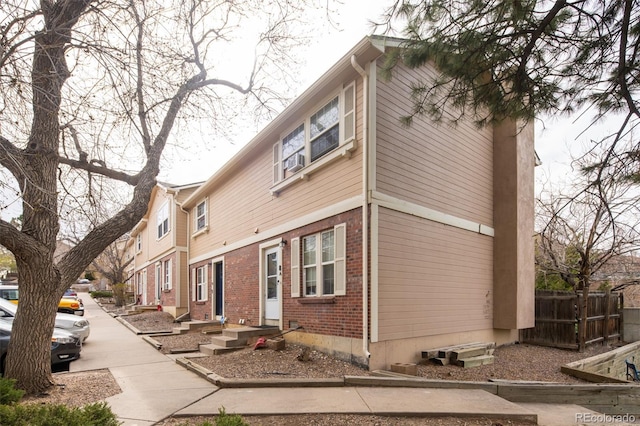 view of front facade with brick siding and fence