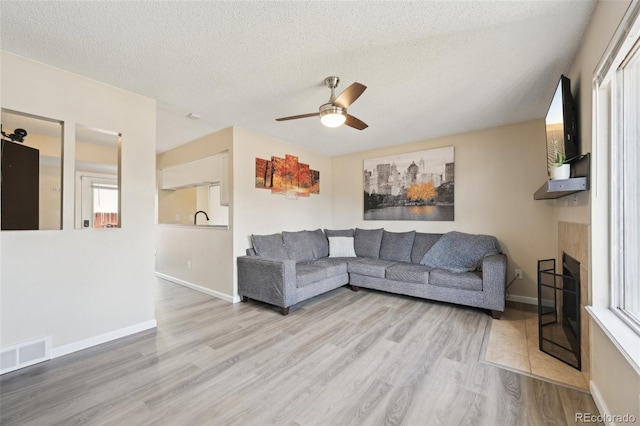 living room with visible vents, baseboards, a fireplace, wood finished floors, and a textured ceiling