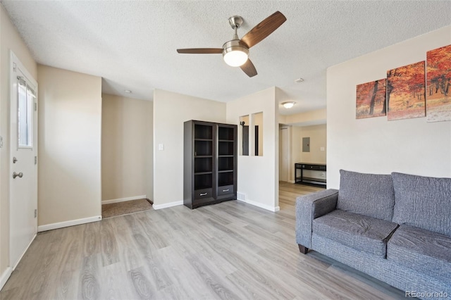 living room featuring electric panel, a textured ceiling, wood finished floors, baseboards, and ceiling fan