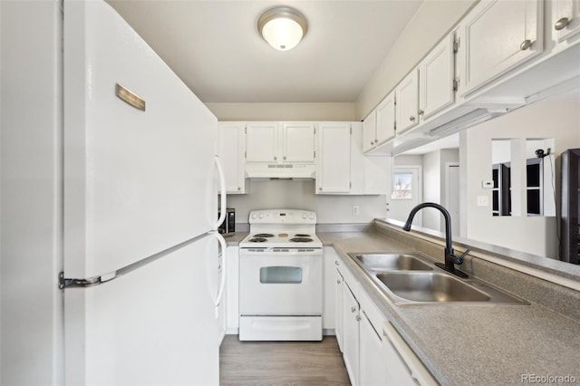 kitchen with white appliances, wood finished floors, a sink, under cabinet range hood, and white cabinetry