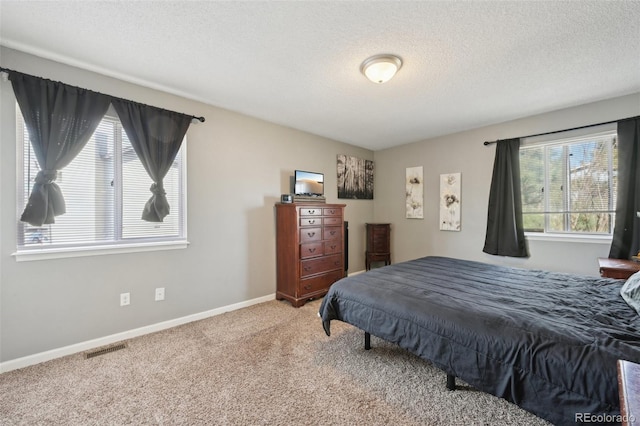 bedroom featuring visible vents, baseboards, carpet, and a textured ceiling