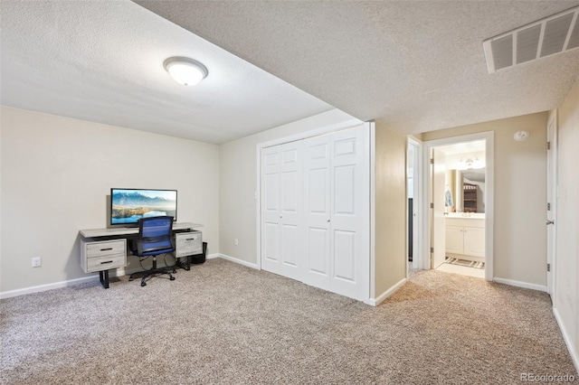 carpeted home office with visible vents, baseboards, and a textured ceiling