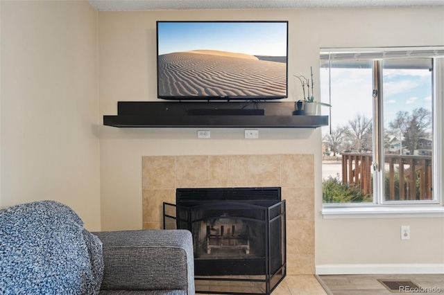 interior details featuring a tiled fireplace, visible vents, and baseboards