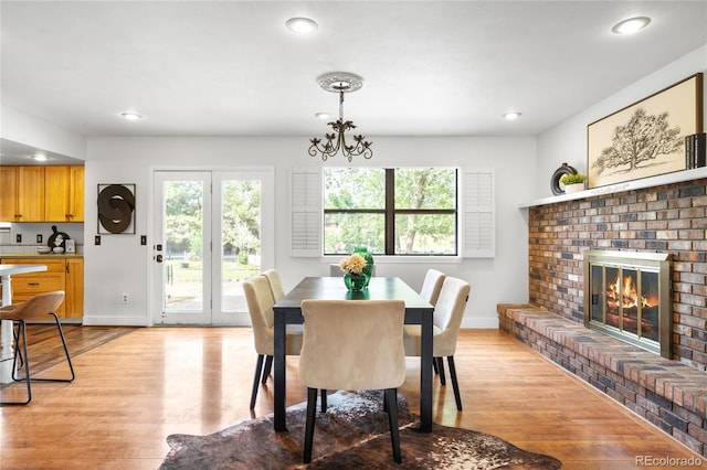 7603 W Coal Mine Pl, Littleton, CO 80128 - dining area featuring light wood-style floors, a fireplace, recessed lighting, and a chandelier