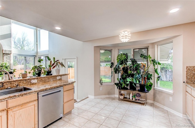 kitchen with stainless steel dishwasher, a sink, light brown cabinets, baseboards, and recessed lighting