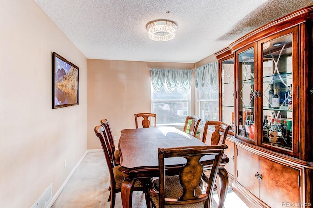 dining space with a textured ceiling, carpet, and baseboards