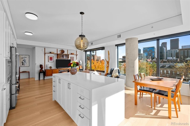 kitchen with white cabinetry, light hardwood / wood-style flooring, a center island, and hanging light fixtures