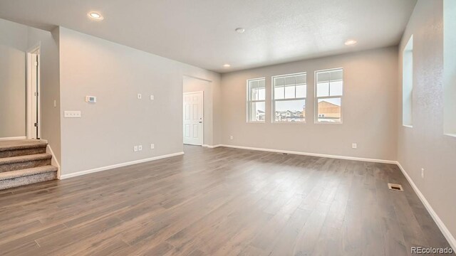 empty room featuring recessed lighting, visible vents, baseboards, stairs, and dark wood finished floors